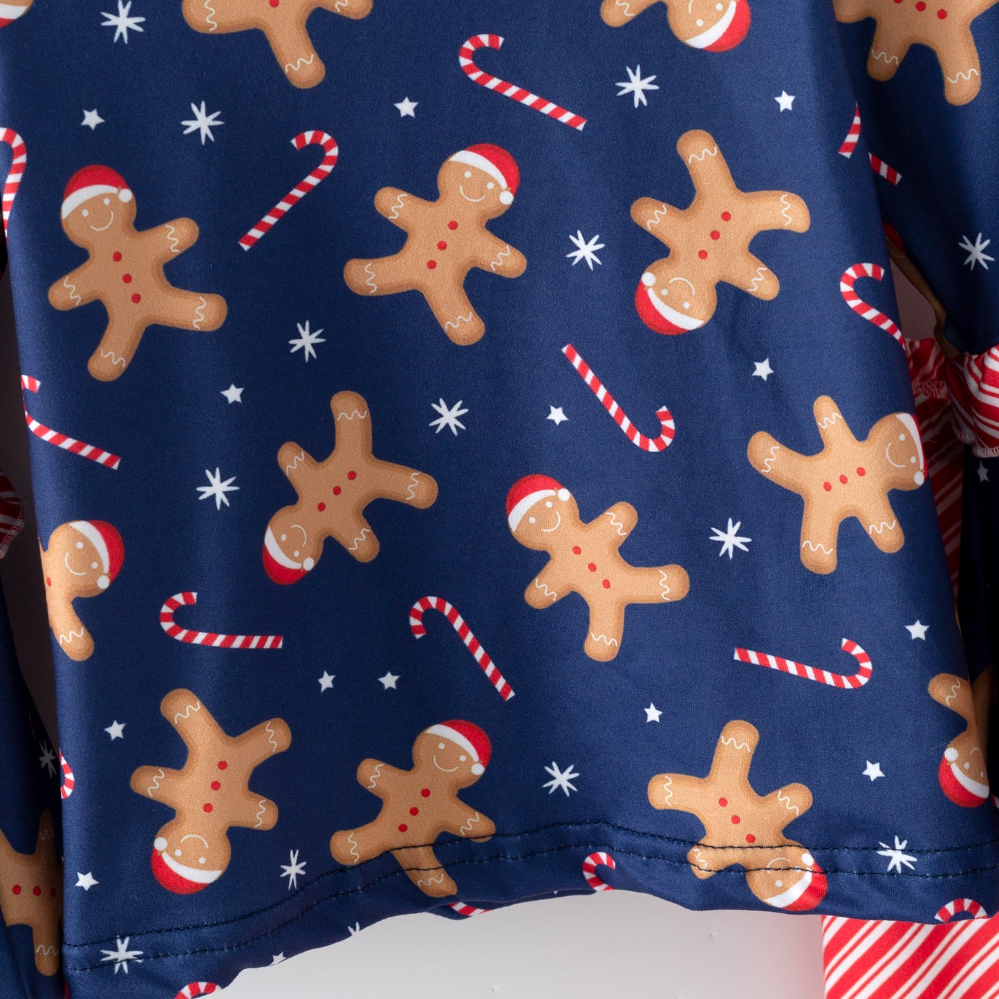 Christmas-themed fabric with gingerbread men, candy canes, and snowflakes on a blue background.