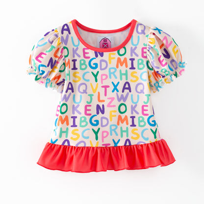 Children's top with colorful alphabet pattern on a white background