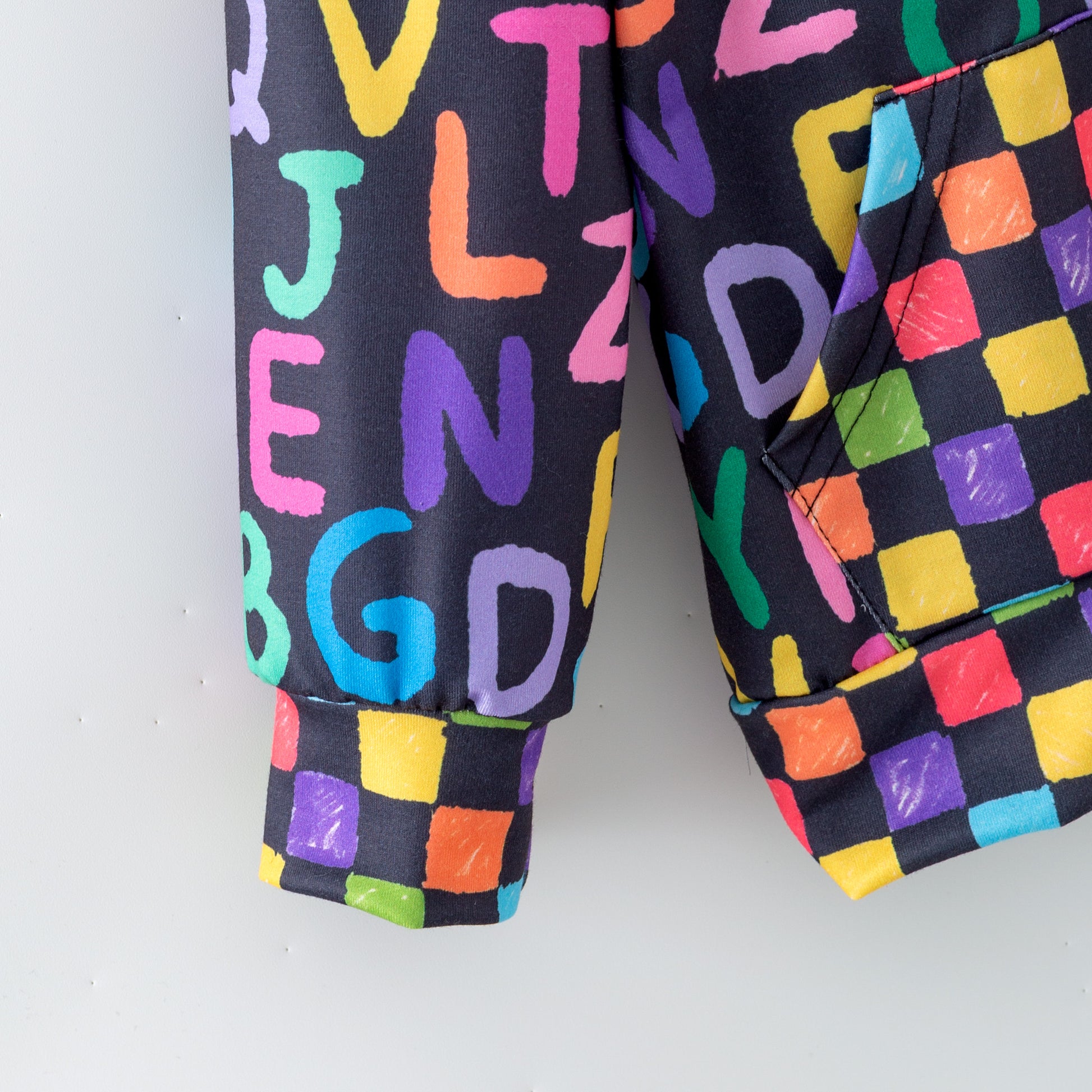 Sleeve of Children's zipper hoodie with colorful letter and block patterns on a white background