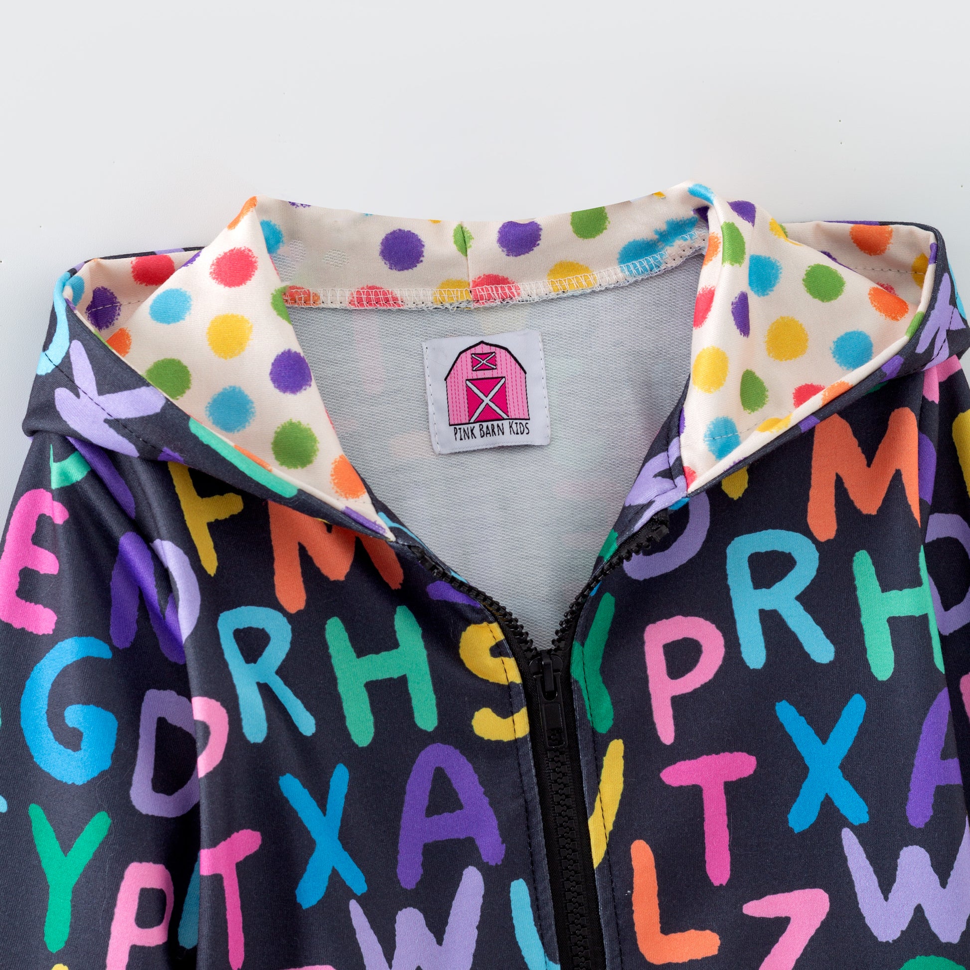 Children's zipper hoodie with colorful letters and polka dot lining on a white background