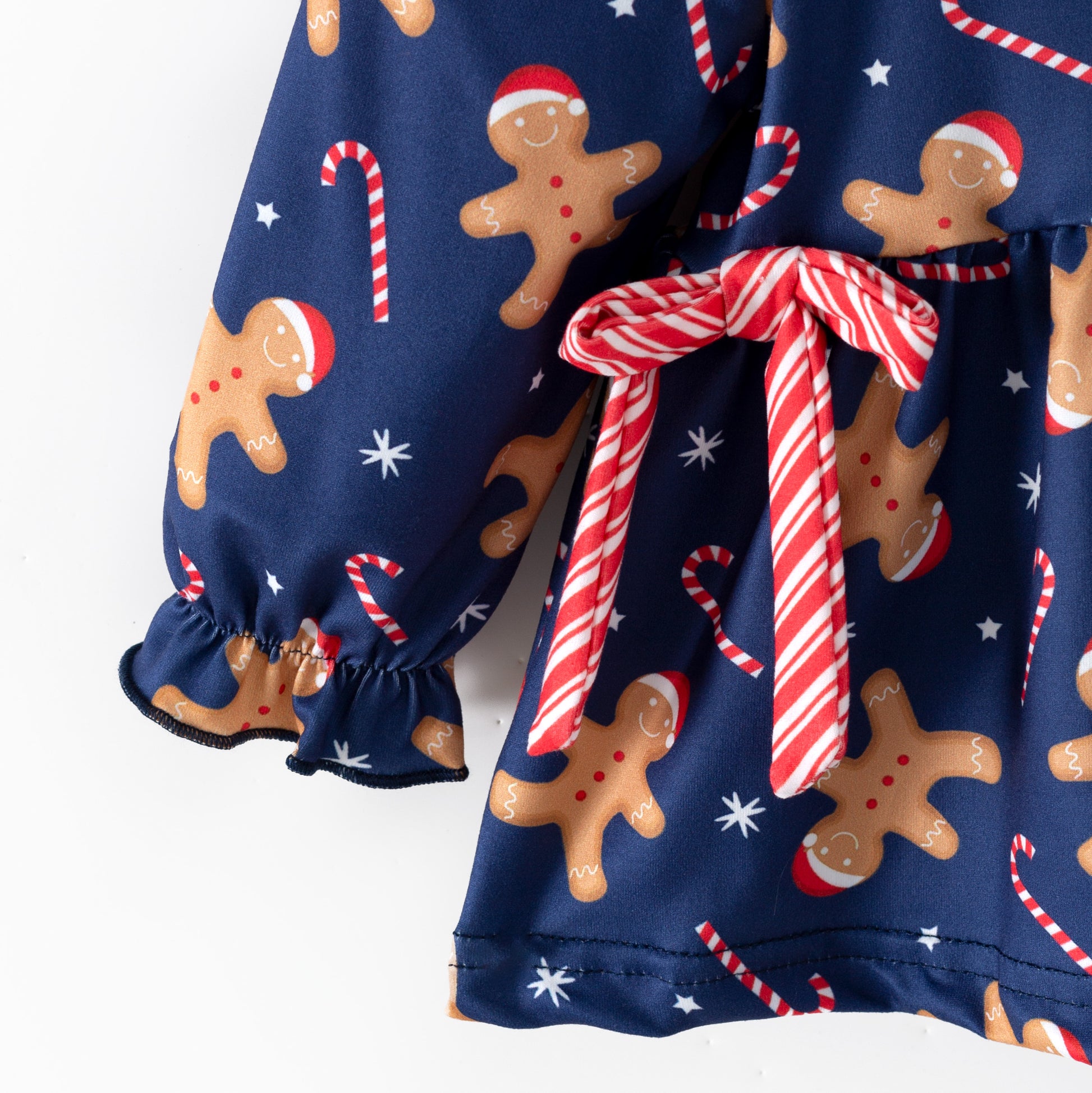 Children's Christmas-themed outfit with gingerbread pattern and candy cane details on a blue background