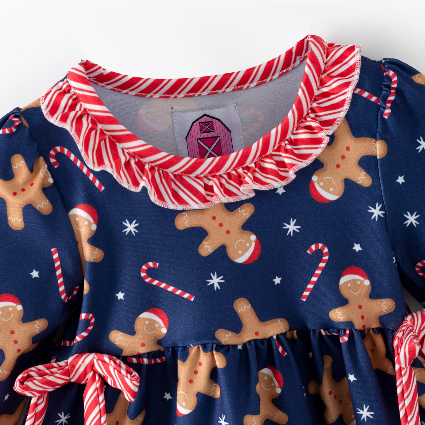 Children's Christmas-themed outfit with gingerbread pattern and candy cane details on a blue background