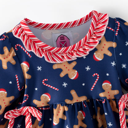Children's Christmas-themed outfit with gingerbread pattern and candy cane details on a blue background