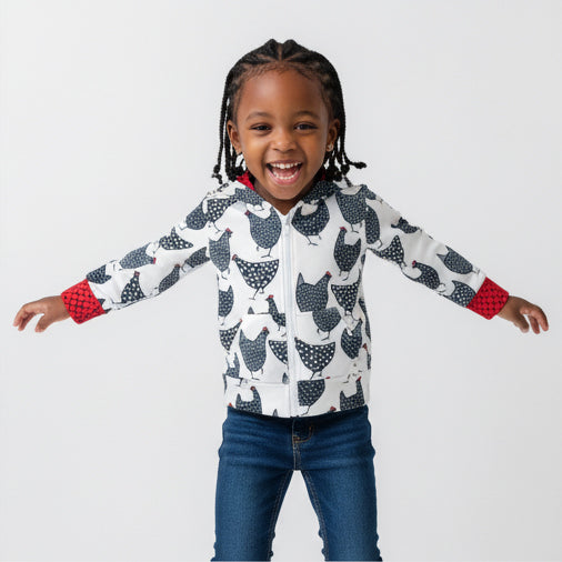 Child wearing a chicken patterned jacket with arms outstretched on a plain background
