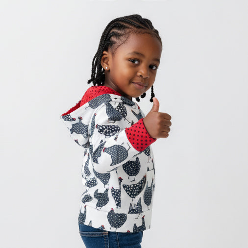 Child wearing a chicken patterned jacket with red interior, giving a thumbs-up on a light gray background