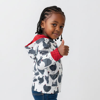 Child wearing a chicken patterned jacket with red interior, giving a thumbs-up on a light gray background