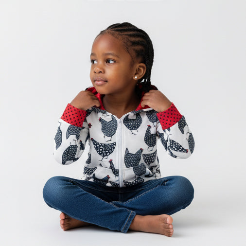 Child wearing a hoodie with chicken pattern and red cuffs on a white background