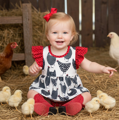 Child in a farm setting with chickens and hay