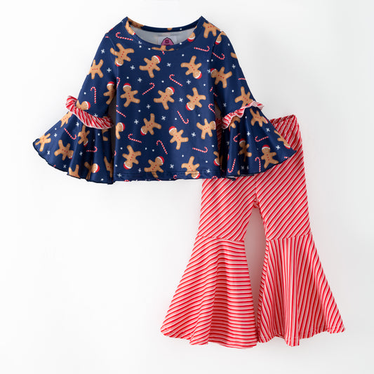 Children's outfit with navy top with gingerbread pattern and red striped pants on a white background