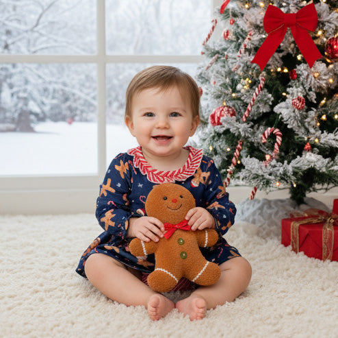 Child holding a gingerbread toy in front of a decorated Christmas tree.