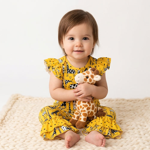 Baby wearing Giraffe Romper sitting on rug. White background