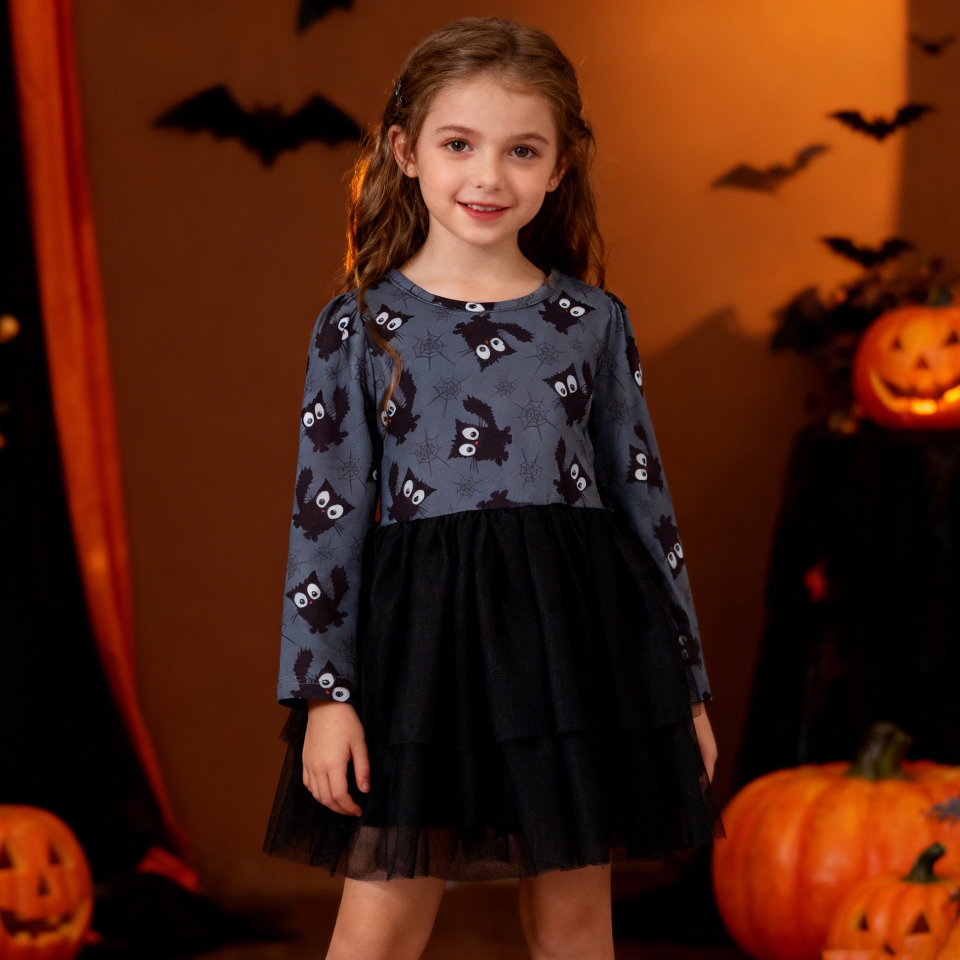 Young girl in a Halloween-themed outfit with pumpkins and bats in the background
