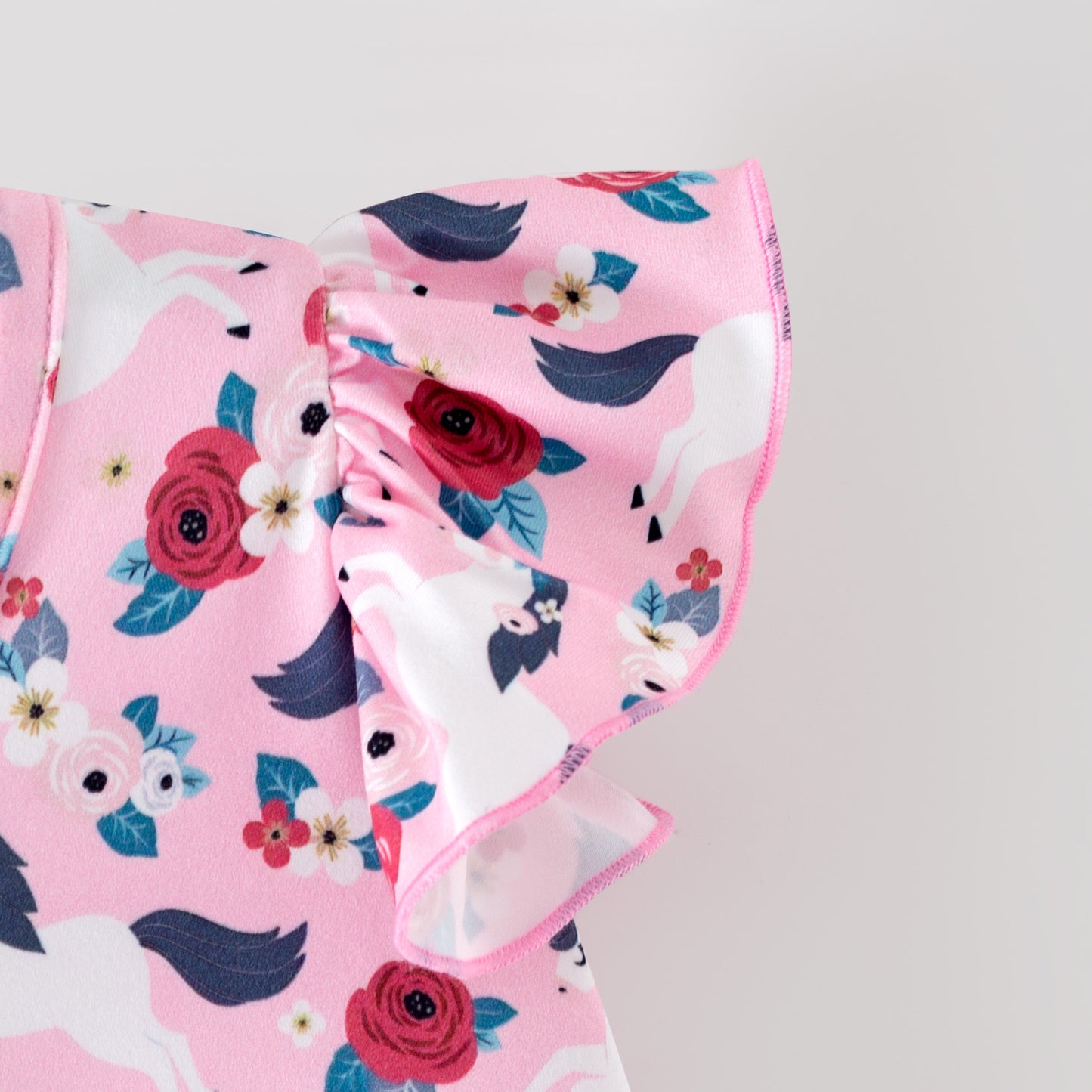 Pink floral baby romper with white horses on a pink background