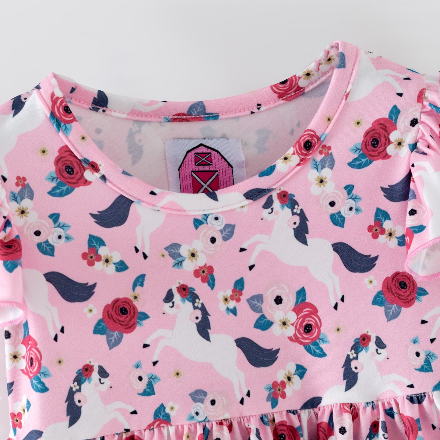 Pink floral baby romper with white horses on a pink background