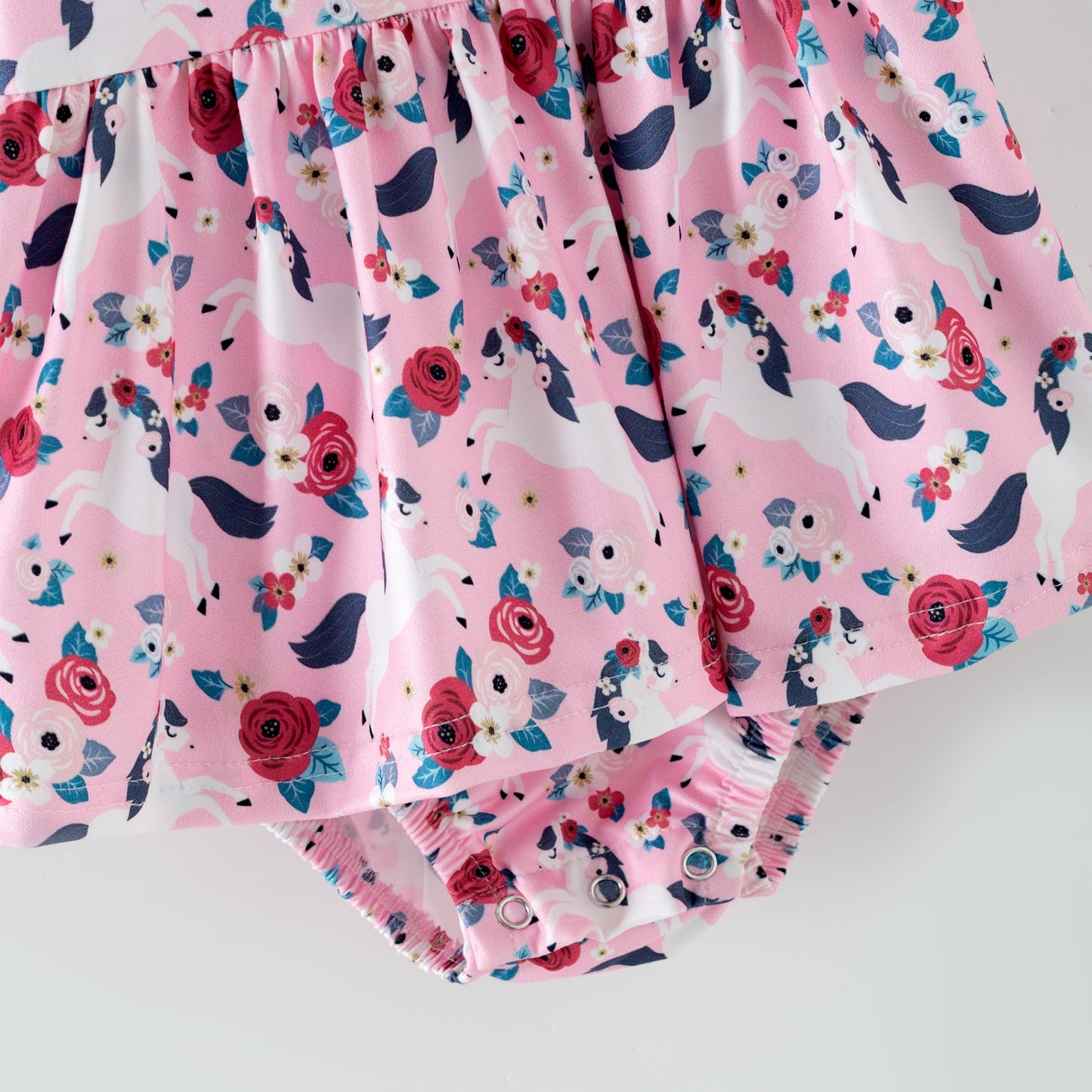 Pink floral baby romper with white horses on a pink background