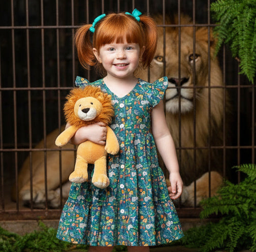 Child holding a lion plush toy with a lion in the background