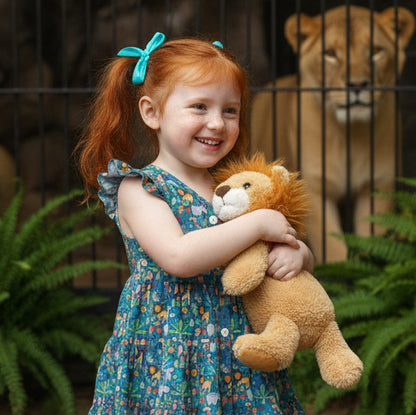 Child holding a lion plush toy with a lion in the background