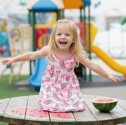 Child in a pink dress with watermelon pattern at a playground