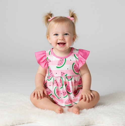 Baby wearing a pink watermelon print onesie on a white background