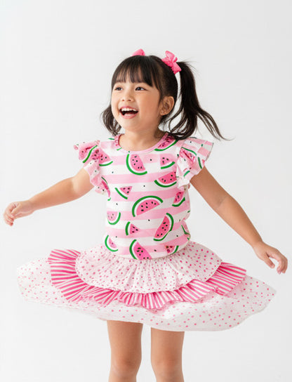 Child wearing a pink dress with watermelon pattern on a white background