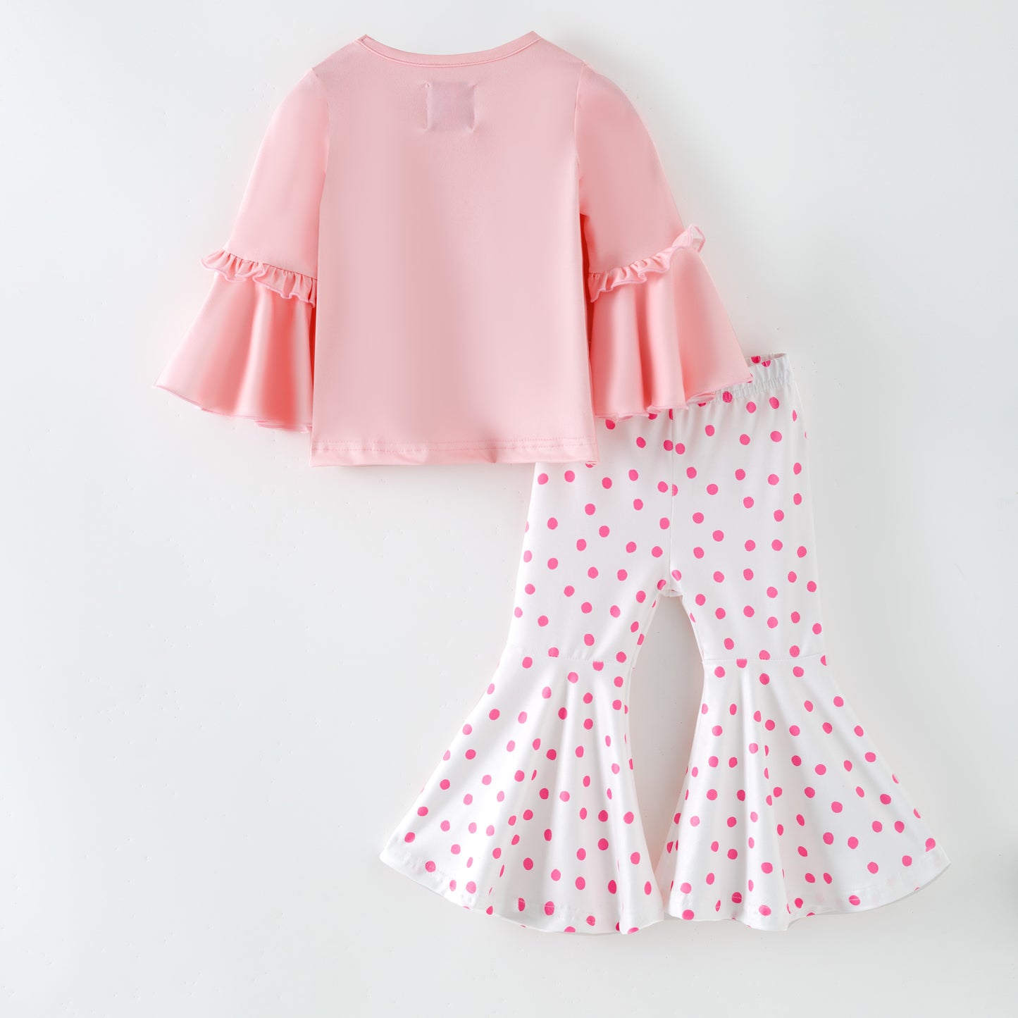 Pink top and polka dot pants on a white background Back of outfit