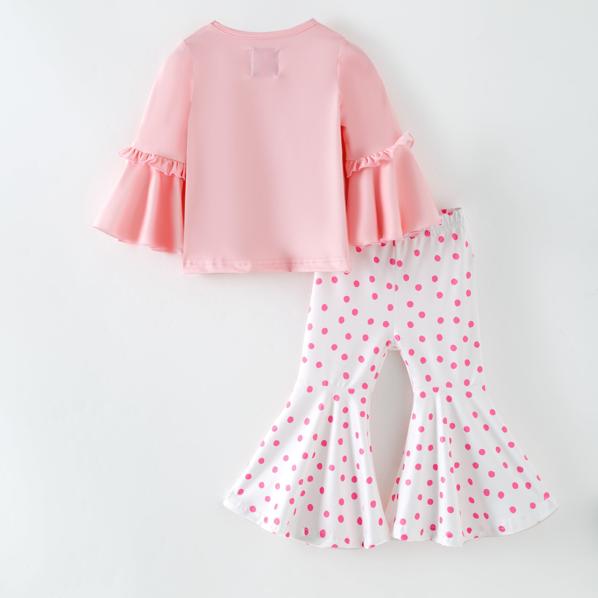 Pink top and polka dot pants on a white background Back of outfit