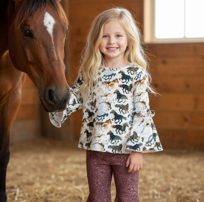 Young girl standing next to a horse in a stable