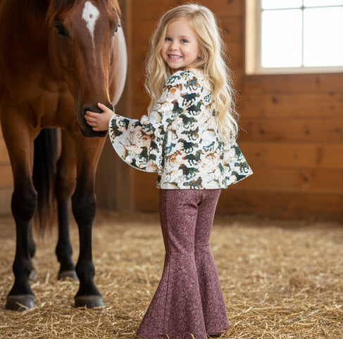 Young girl standing next to a horse in a stable